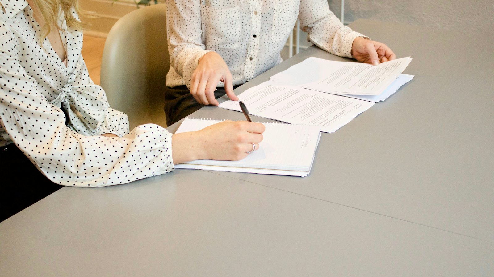Zwei Personen unterschreiben Dokumente an einem Tisch